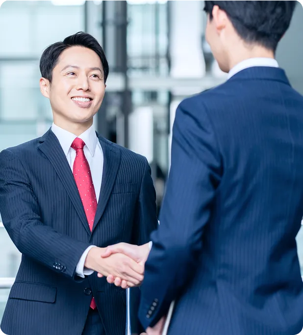若手社員とベテラン社員が握手している画像